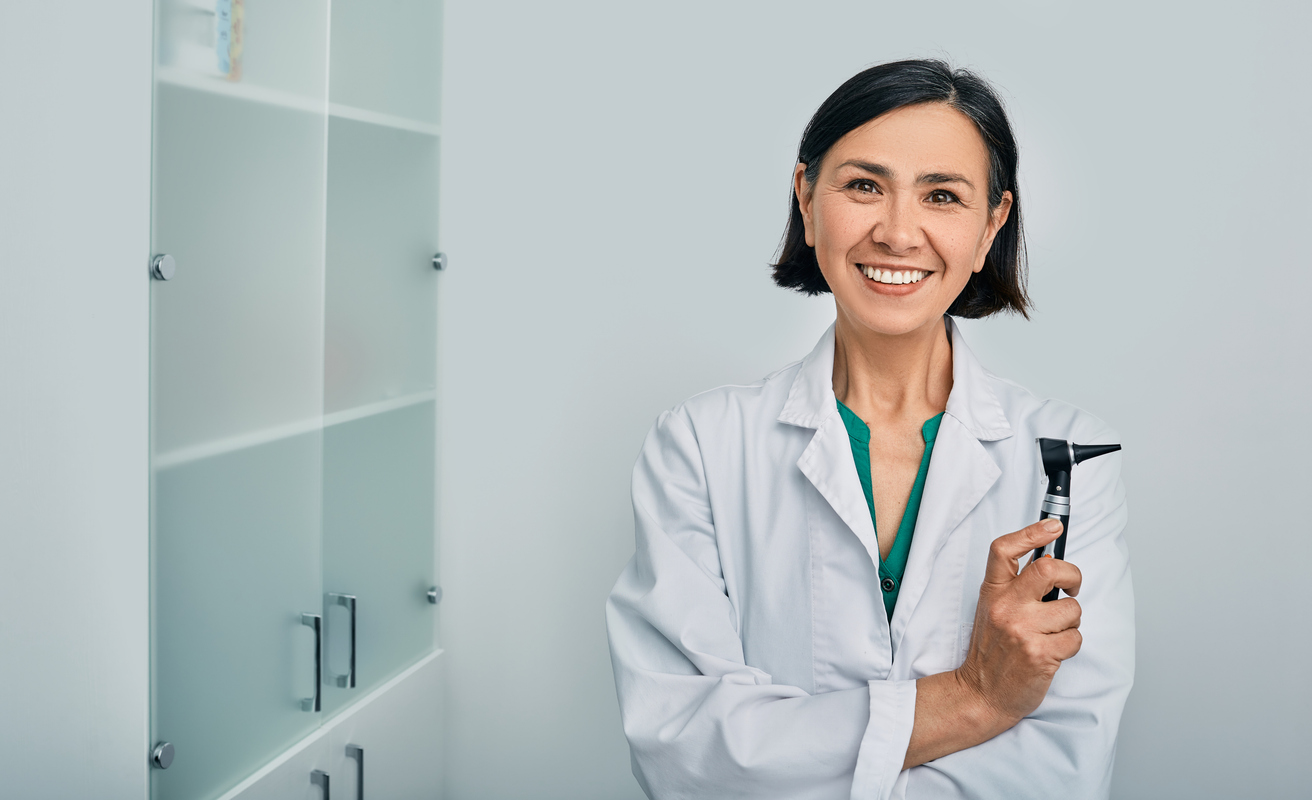 Smiling audiologist holding an otoscope